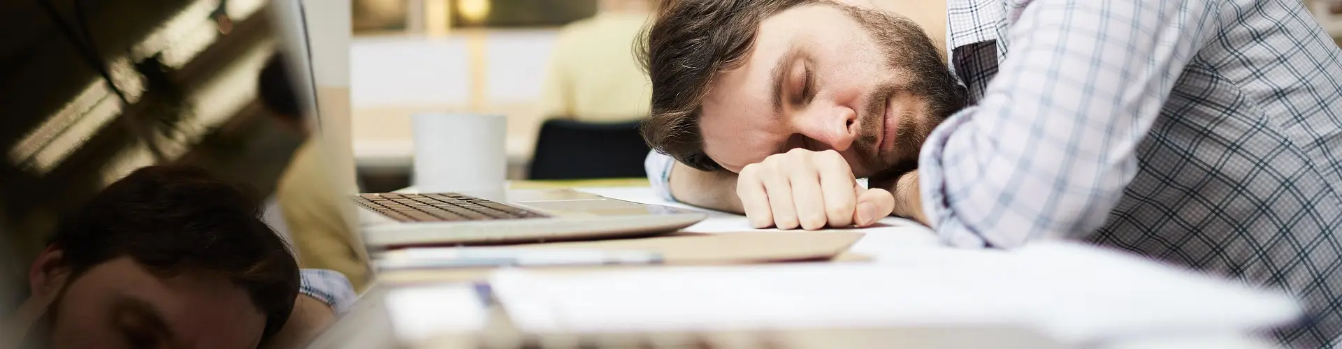 "Mann schläft auf Schreibtisch"