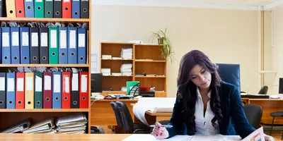 "Frau sitzt in einem Büro und liest eine Zeitung"