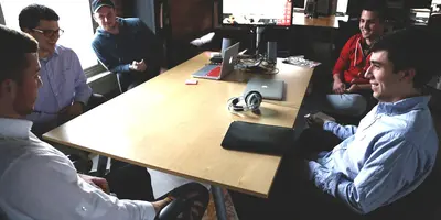 "Menschen die im Kreis am Tisch sitzen und reden"
